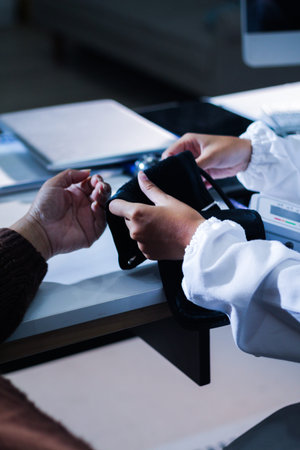 A doctor's hands carefully taking a patient's blood pressure using a sphygmomanometer.の写真素材