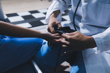 Doctor in hospital using manual blood pressure monitor to measure woman patient blood pressure and pulse.の写真素材