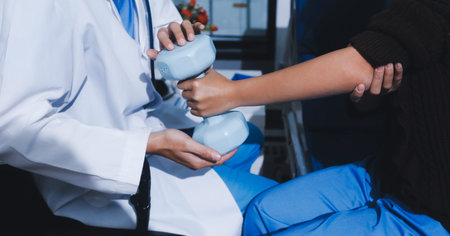 Unrecognizable person uses blue hand weight during physical therapy sessionの写真素材