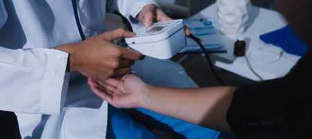 Doctor in hospital using manual blood pressure monitor to measure woman patient blood pressure and pulse.の写真素材