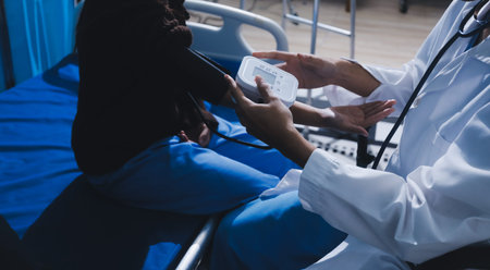 Doctor in hospital using manual blood pressure monitor to measure woman patient blood pressure and pulse.の写真素材