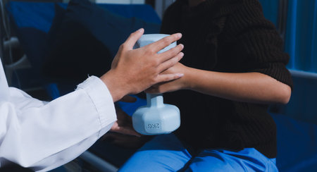 Unrecognizable person uses blue hand weight during physical therapy sessionの写真素材