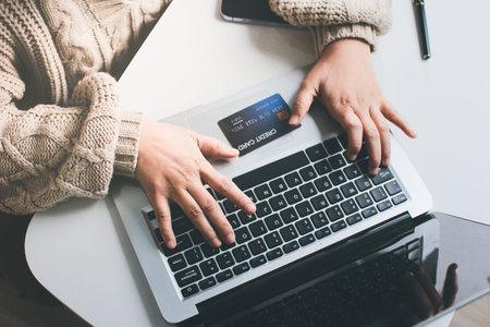 Close up cropped man use laptop pc computer hold credit card speak on cell phone sit at table in coffee shop cafe relax rest in restaurant in free time indoor Freelance mobile concept Focus on objectの写真素材