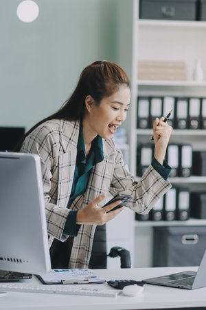 Determined asian businesswoman works late in a modern office, confidently analyzing data on her...