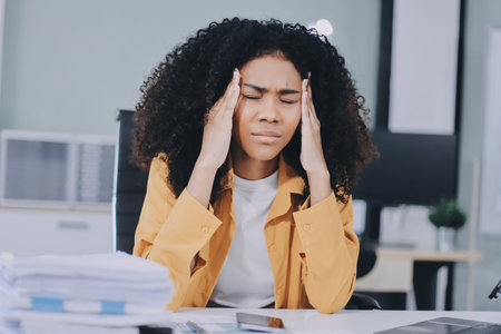 Businesswoman experiencing discomfort and pain in her lower back while sitting at her desk, working...