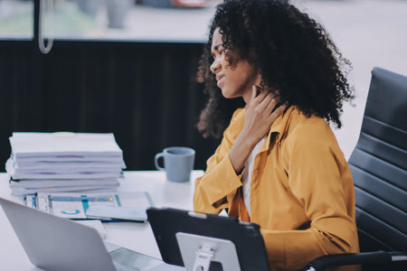 Businesswoman experiencing discomfort and pain in her lower back while sitting at her desk, working...