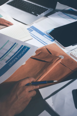 Professional photo of a person's hands reviewing a contract or legal document on a desk, for concepts of business, finance, and legal affairsの写真素材