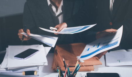 Professional photo of a person's hands reviewing a contract or legal document on a desk, for...