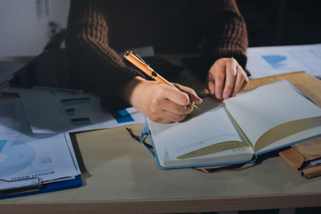 Close-up of businessman's hands making notes, mobiles, chart, desk, office