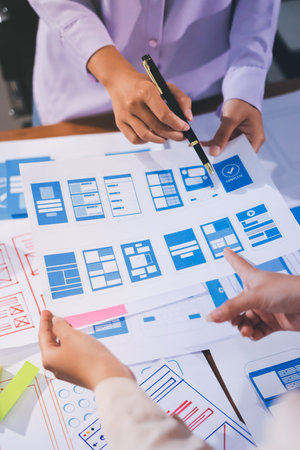 Close up ux developer and ui designer brainstorming about mobile app interface wireframe design on...