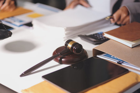 Gavel with Justice lawyers having team meeting at law firm in background. Notary with client in...