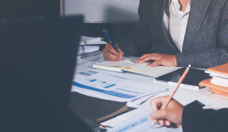 Professional photo of a person's hands reviewing a contract or legal document on a desk, for...