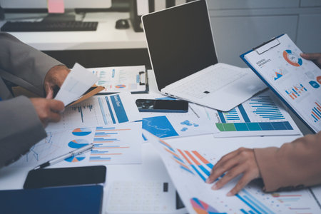 Business colleagues analyzing financial charts and reports on the table while having a focused...