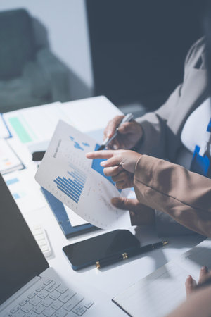 Business colleagues analyzing financial charts and reports on the table while having a focused...