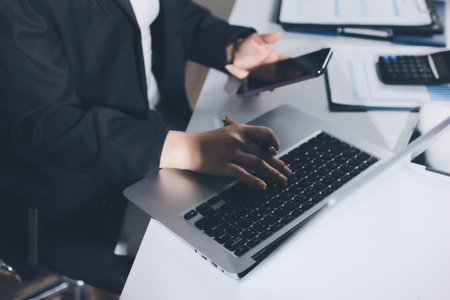 Auditors collaborating in modern office, analyzing financial documents and using calculator with a...
