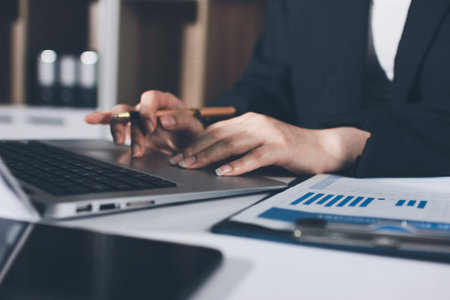 Auditors collaborating in modern office, analyzing financial documents and using calculator with a...