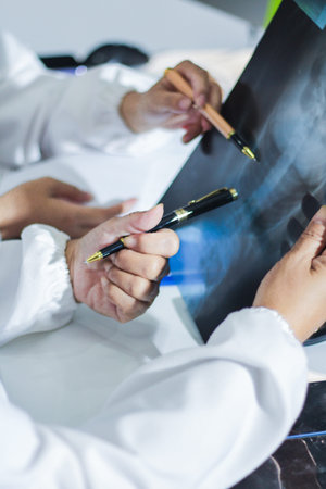 Medical team having a meeting with doctors in white lab coats and surgical scrubs seated at a table...