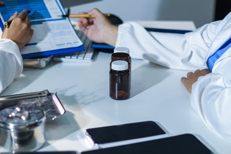 Medical team having a meeting with doctors in white lab coats and surgical scrubs seated at a table...