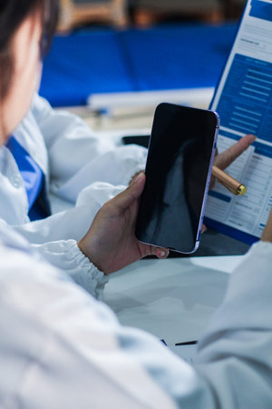 Medical team having a meeting with doctors in white lab coats and surgical scrubs seated at a table...