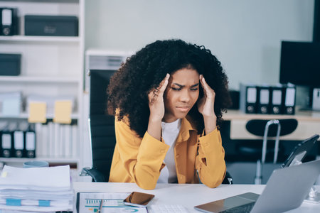 Businesswoman experiencing discomfort and pain in her lower back while sitting at her desk, working...