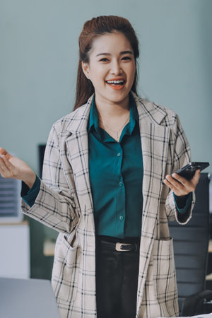 Determined asian businesswoman works late in a modern office, confidently analyzing data on her...