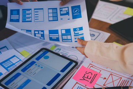 Close up ux developer and ui designer brainstorming about mobile app interface wireframe design on...