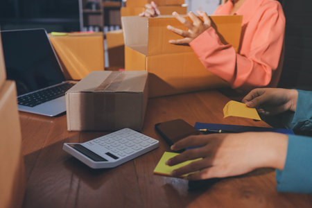 Startup SME small business entrepreneur of freelance Asian woman wearing apron using laptop and box...