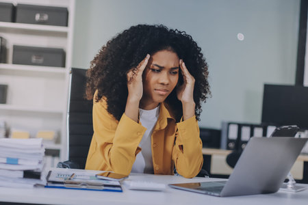Businesswoman experiencing discomfort and pain in her lower back while sitting at her desk, working...