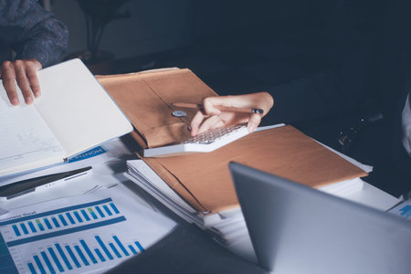 Professional photo of a person's hands reviewing a contract or legal document on a desk, for...