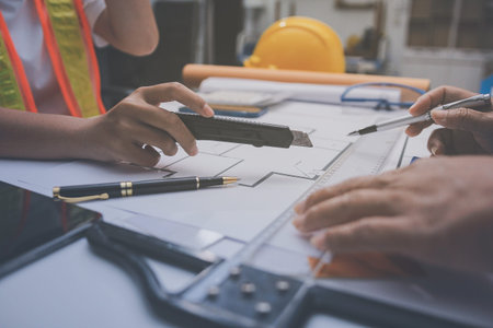 engineer and an architect reviewing blueprints and construction plans together at a bustling...