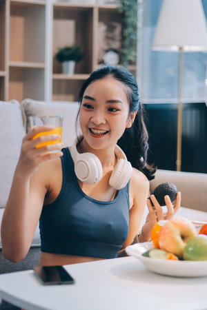 Fit young Asian women in activewear sitting on yoga mat and eating fresh vegetable salad after...