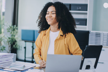 Pretty female freelancer working on laptop while sitting on modern coworking background