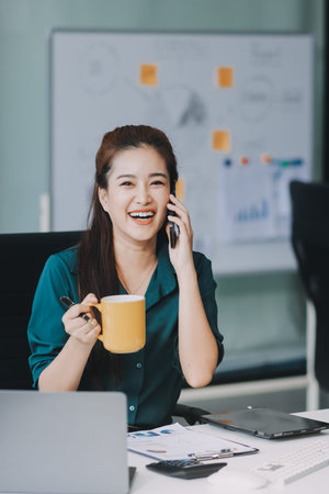 Determined asian businesswoman works late in a modern office, confidently analyzing data on her...