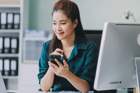 Determined asian businesswoman works late in a modern office, confidently analyzing data on her...