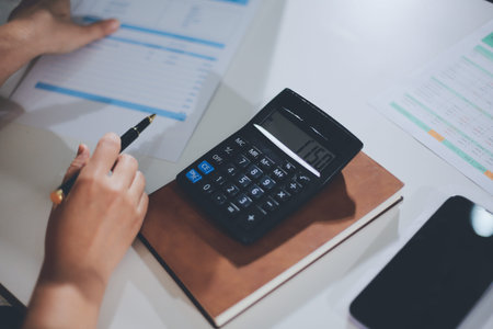 Business woman using calculator to calculate financial report, working at office with laptop...