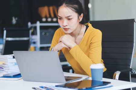 Young professional woman suffering from headache while analyzing financial charts and graphs on...