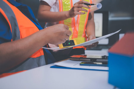 engineer and an architect reviewing blueprints and construction plans together at a bustling construction site