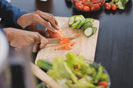 Young nutritionist showing bell peppers during an online video call consulting about healthy eating, sitting at home at a table with vegetables, laptop and measuring tape