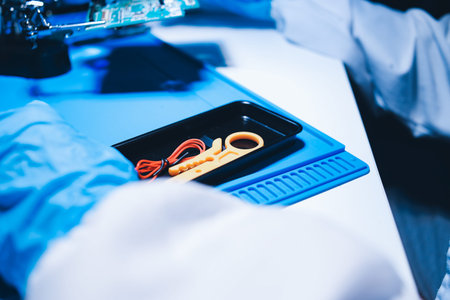 Hands in white gloves carefully repair a broken mobile device, meticulously working on the intricate internal electronics and circuit board