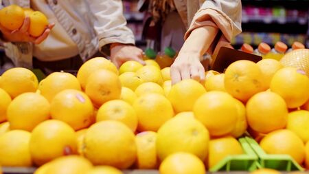 A man and a woman are buying oranges in a supermarketの写真素材