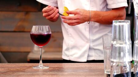 Arms of a bartender who is making a cocktail with an orangeの写真素材
