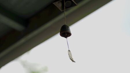A close-up of a small traditional bell in the wind in Asiaの写真素材