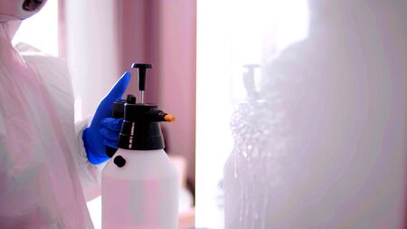 Arm of a person who is using a big spray to clean a white areaの写真素材