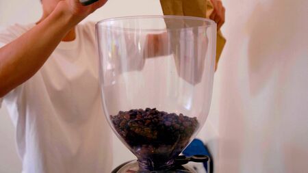 Hands of a man who is puting coffee beans in a machineの写真素材