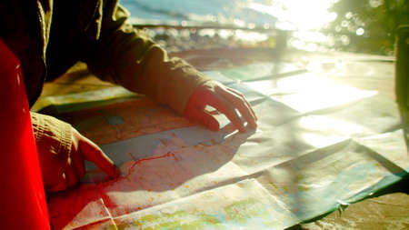 The hands of a man on a map with the sunの写真素材