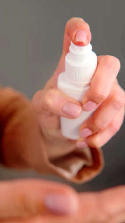 A close-up on the hands of a woman who is using a sprayの写真素材