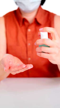 A vertical photo of a young woman who is using a gel bottleの写真素材