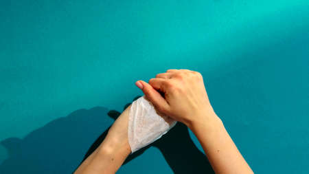 A top view of the hands of a woman who is cleaning her hands with a wipeの写真素材