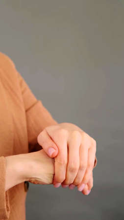 A vertical photo of a young woman who is rubbing her hands