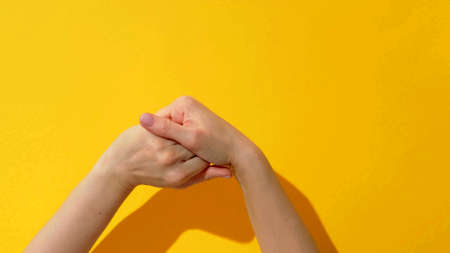 Top view of a woman who is rubbing her hands on a yellow backgroundの写真素材